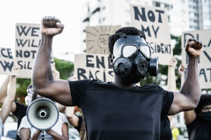 Activist wearing gas mask protesting against racism and fighting for equality - Black lives matter demonstration on street for justice and equal rights - Blm international movement concept