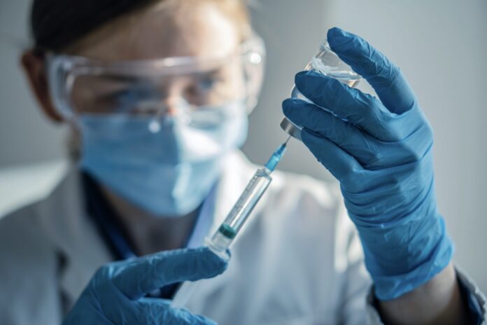 A doctor with a research approach collects a drug into a syringe for the next injection in a medical laboratory. Scientist of a pharmaceutical company to create new drugs for fighting viruses