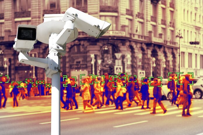 Video surveillance and technology. Video surveillance camera on the background of people walking on a pedestrian crossing. Face recognition effect. Blur